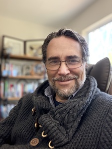 Brad Bull with beard and glasses, wearing a collared sweater