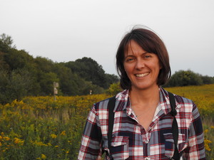 a photo of a white woman with short brown hair in a meadow