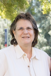 Author standing against green trees