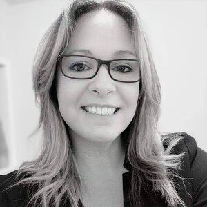 Black and white photo of the author, DA BUTLER, below shoulder length, blonde hair, dark rimmed glasses.