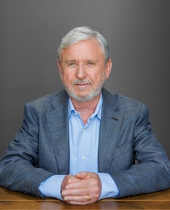 Ray Tye, author of Travis Heights, seated in blazer with hands clasped