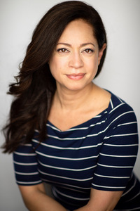 A brunette woman wearing a blue and white striped shirt.