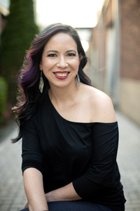 A dark haired Asian woman in black smiling at the camera 