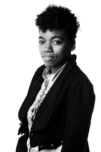 Phoebe Sinclair, African-American author with brown skin, curly hair long on the top and short on the sides, wearing a jean jacket