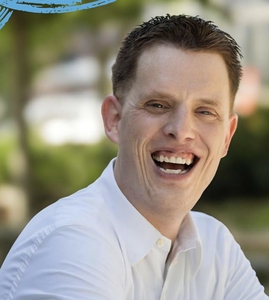 Patrick Stapleton smiling outdoors in a white button-down shirt.