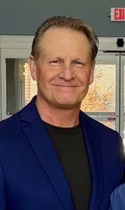 An image of Tim Robinson wearing a suit coat