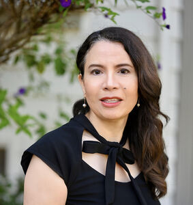 Woman with long wavy hair and bow tie dress