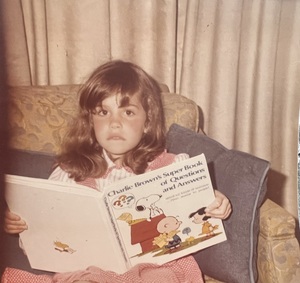 kodakchrome snapshot of a 6 year old girl in a dress holding her then-favorite book, "charlie brown's super book of questions and answers"s 