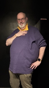Brian Watson, dressed in purple and yellow, against a black background