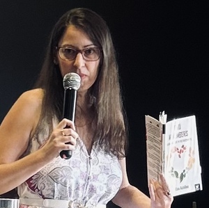 Liza Achilles speaking into mic at poetry event