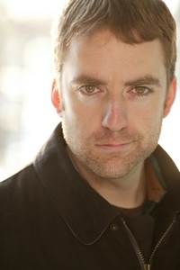 Man with five o’clock shadow in brown coat