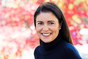 smiling white woman with dark hair and pink background