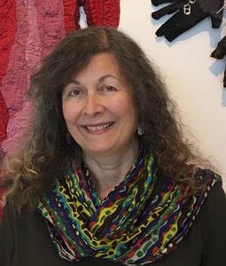 A smiling woman with long dark hair and a colorful, patterned scarf.