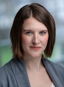 Rachel King has short light brown hair, green eyes, and is smiling. She wears a purple dress.