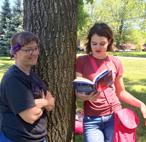 Teacher Lou Hopping listens to a recent 8th grade graduate read aloud from Wishtree by Katherine Applegate.