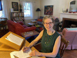 woman in green top sitting at at table with papers on it