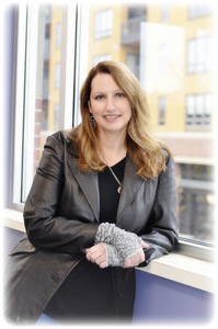 Headshot of Anna August leaning on a windowsill at library