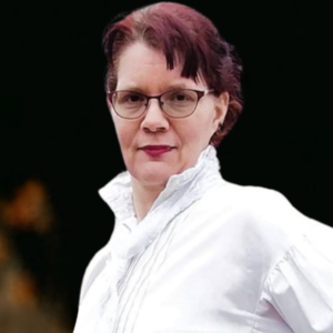 Middle-aged person with glasses, wearing white shirt, standing outdoors