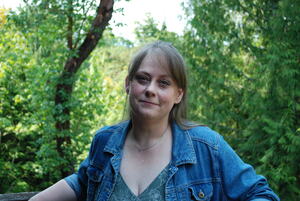 The author, Alie Dumas-Heidt, standing against a background of trees in the PNW forest
