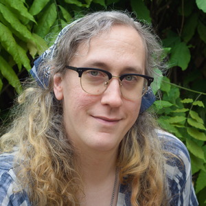 A portrait of Madison in a blue shirt with her hair up in a kerchief