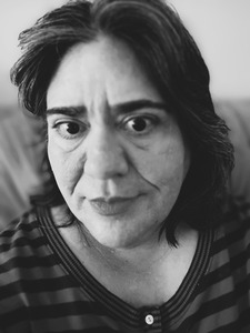 Black and white headshot of poetess Karen Quickley. She is wearing a striped sweater and is middle-aged and Caucasian with dark hair and eyes.