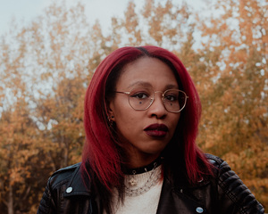 A photo of Jamison Shea, a Black author with red hair and glasses.