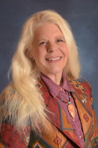 "Dr. Lynda Rogerson smiling in a seated studio headshot, wearing a Western-style outfit with a confident and approachable expression"