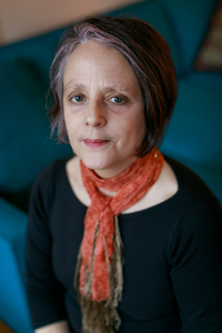 Elizabeth Costello wears an orange scarf and a black shirt.