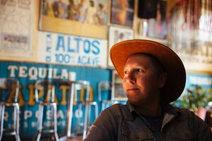 The author is white and wearing a brown hat, with their head turned to the side