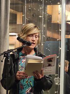 author standing at mic reading from her book of poetry