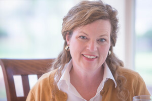 Headshot of Marie Bostwick wearing white blouse and mustard colored cardigan