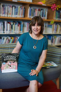 A picture of a woman in a green dress holding a copy of Vampirina Ballerina