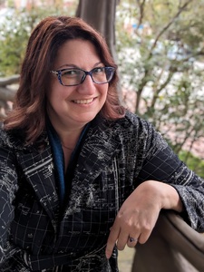 Headshot of a white woman with darkish hair sitting in a gazebo