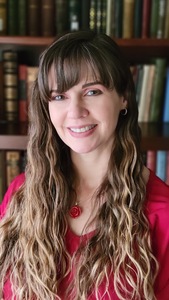 Jolene Gutiérrez standing in a library in front of a bookshelf full of books.