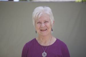 head shot, fuchia color blouse, necklace, smile, grey hair
