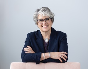 picture of Oona Metz, wearing a blue blazer, leaning on a pink chair