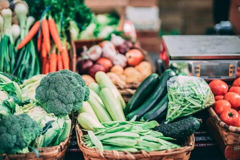 Assorted vegetables in woven baskets, in three rows to the back of the image.
