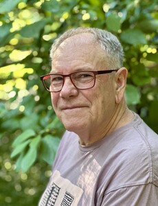 Photo of a white male in his 60's. Grey hair, red glasses, wearing a t-shirt