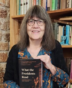 image of co-editor, Marilynn S. Olson, holding a copy of the book What the Presidents Read in front of a bookcase