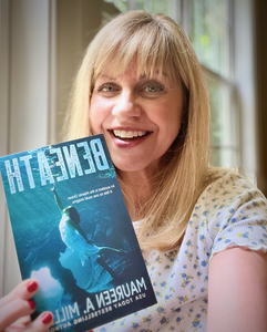 Author Maureen A. Miller holding up her book, BENEATH.