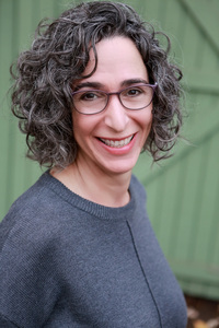 Photo of Miriam in gray sweater against green door