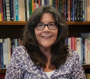 woman with brown hair against bookshelf