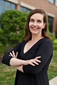 an image of a brunette with her arms crossed outdoors