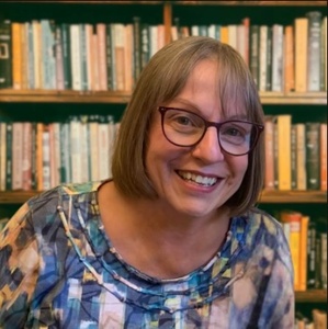 Author smiling in front of bookcase.