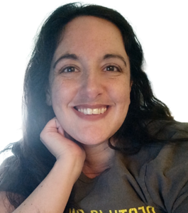 Danielle is a white woman in her 30s with long, black hair and a gray henley. She is smiling at the camera.