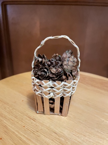 This little basket full of tiny pine cones can be used as a Christmas tree ornament or other decoration..
