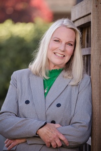 Headshot of Penny Nolan wearing a black and white jacket with a green blouse smiling.