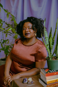 Tatiana sitting in a chair facing camera with purple backdrop