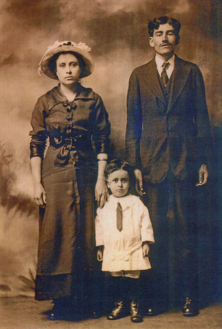 Mother, father and 3 year old child in a formal early 20th Century portrait.