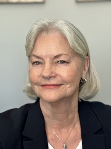 Headshot of Cynthia smiling directly at the camera wearing a navy blue blazer.